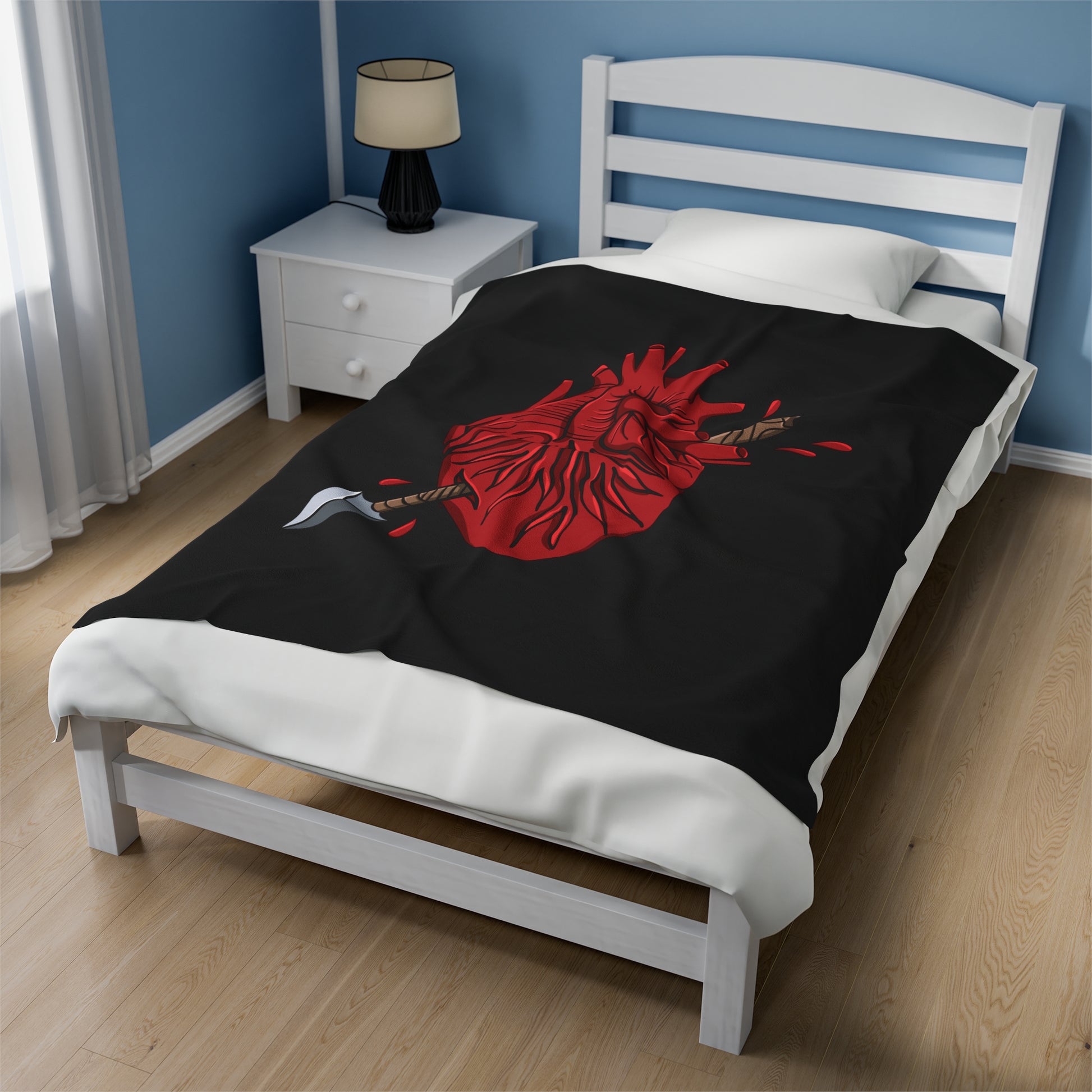 Black blanket with an illustration of an arrow piercing an anatomical heart being used as a bedspread.